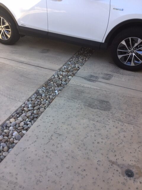 A car parked on the side of a road with gravel.